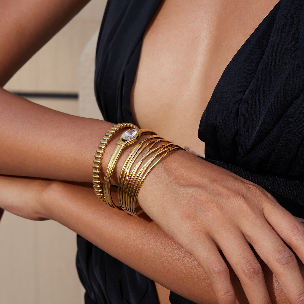 Gold bracelets on a wrist with a neutral background