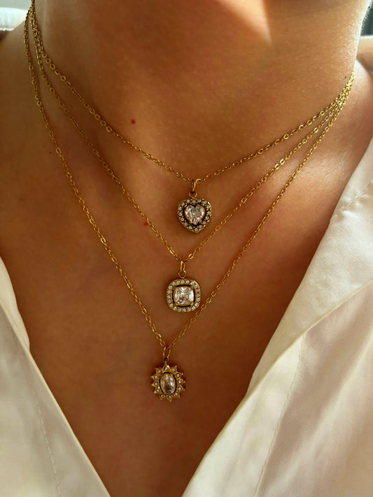 Close-up of a person wearing three gold necklaces with pendant charms– Χονδρική So Cute by Dimi