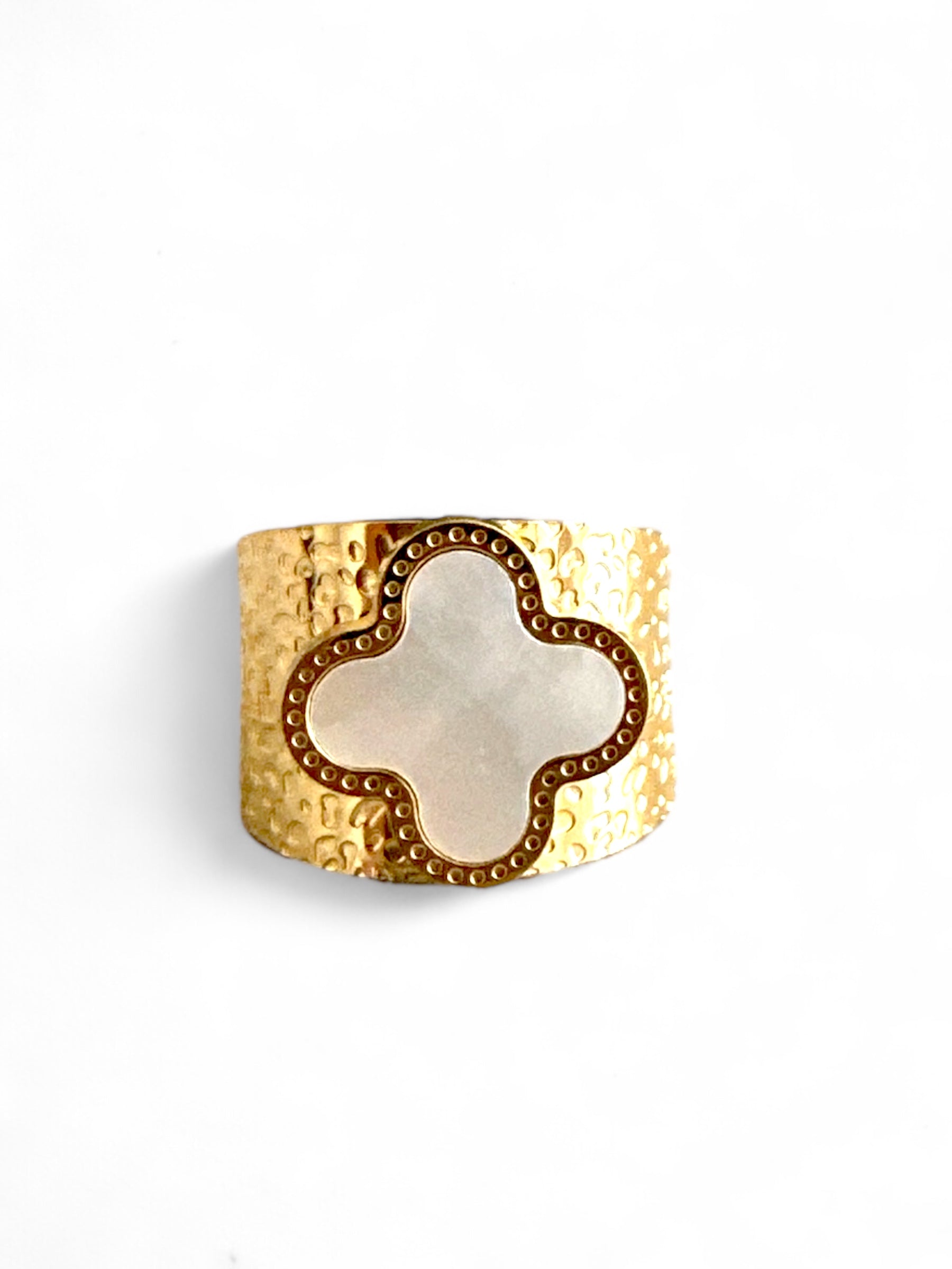 Gold hammered adjustable ring with white clover-shaped mother of pearl on white background, perfect for boho-chic styling.