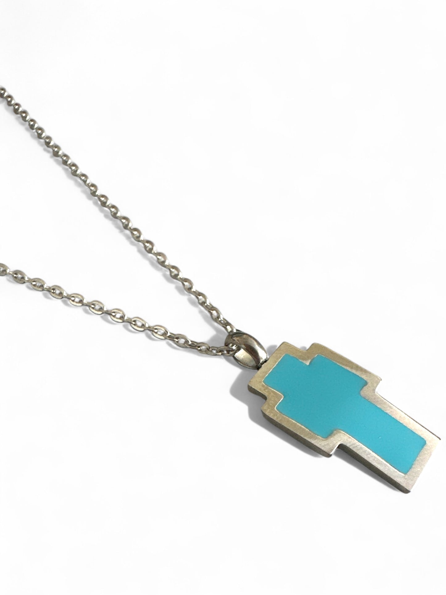 Necklace with a turquoise and silver pendant on a white backgroundPixel Cross Necklace – Ατσάλινο Κολιέ – Χονδρική So Cute by Dimi