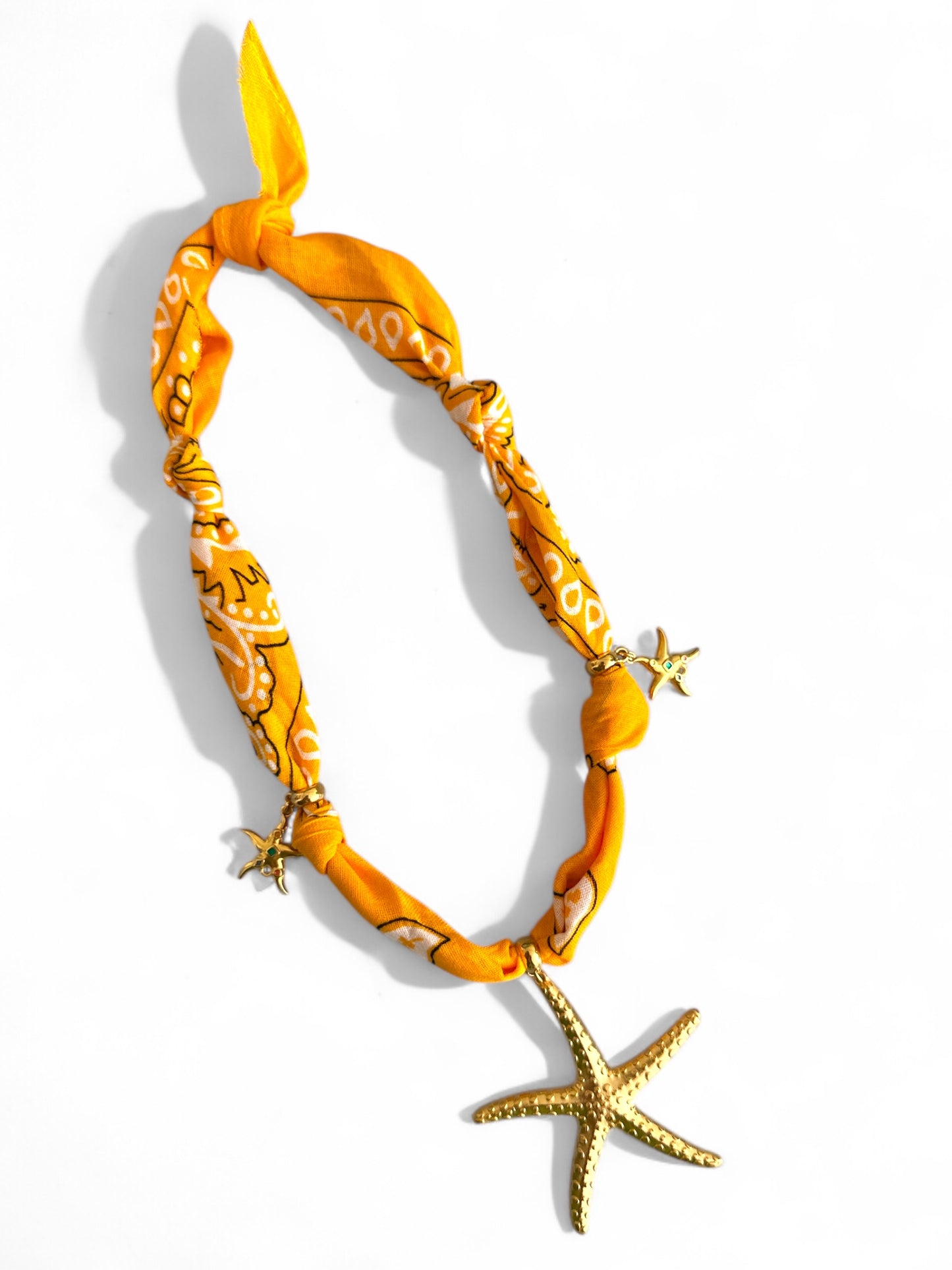 Yellow patterned bandana necklace with starfish decorations on a white background