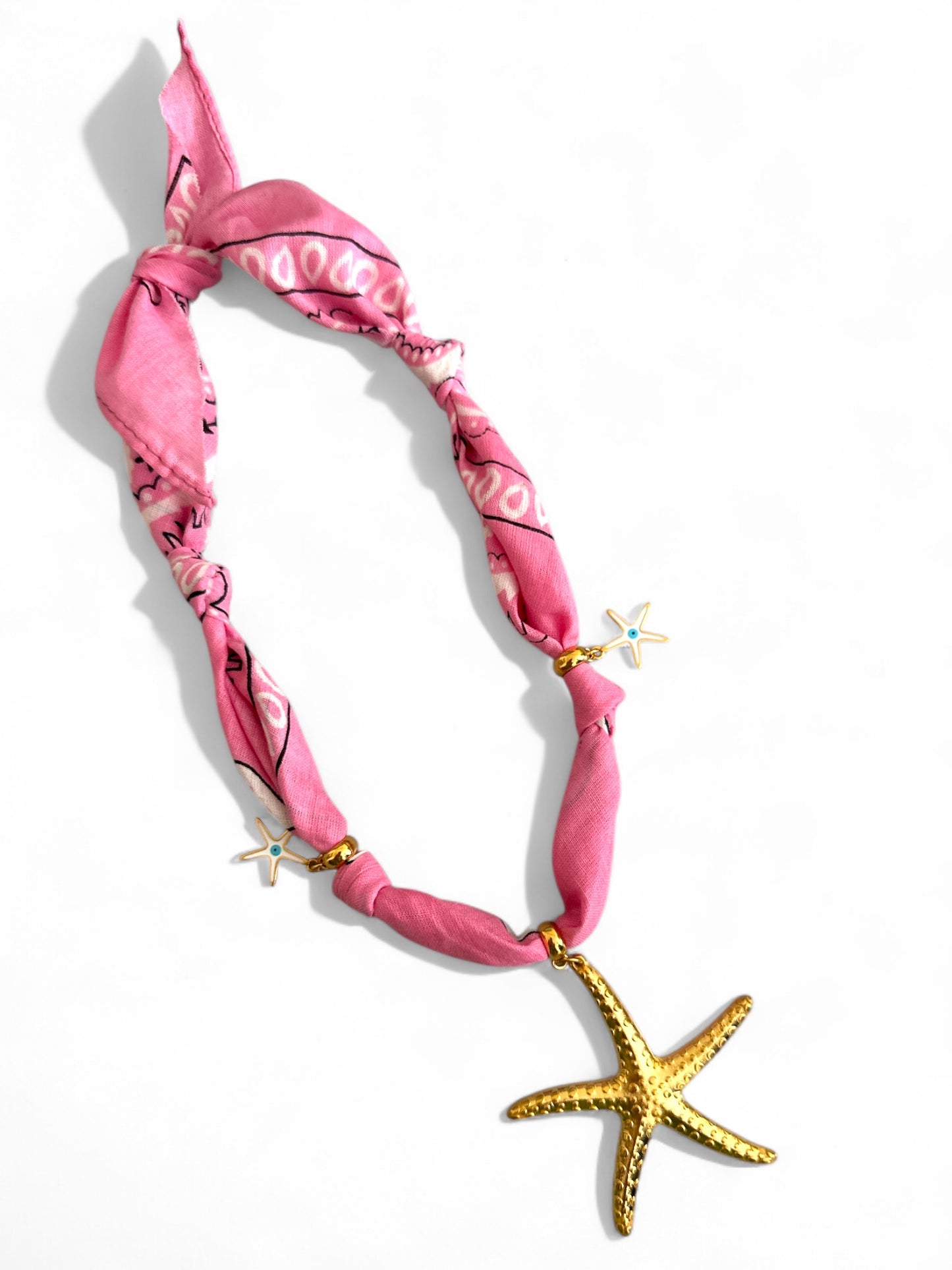 Pink bandana with gold accents and a starfish charm on a white background