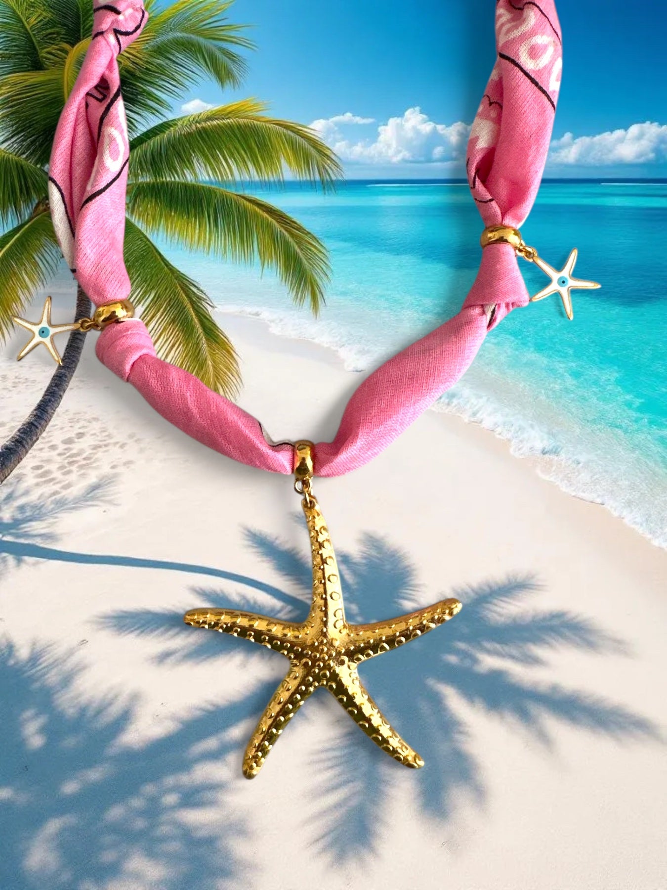 Gold starfish pendant necklace with pink fabric on a tropical beach background