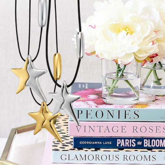 Star-shaped necklaces on a stack of books with flowers in the background- So Cute by DImi