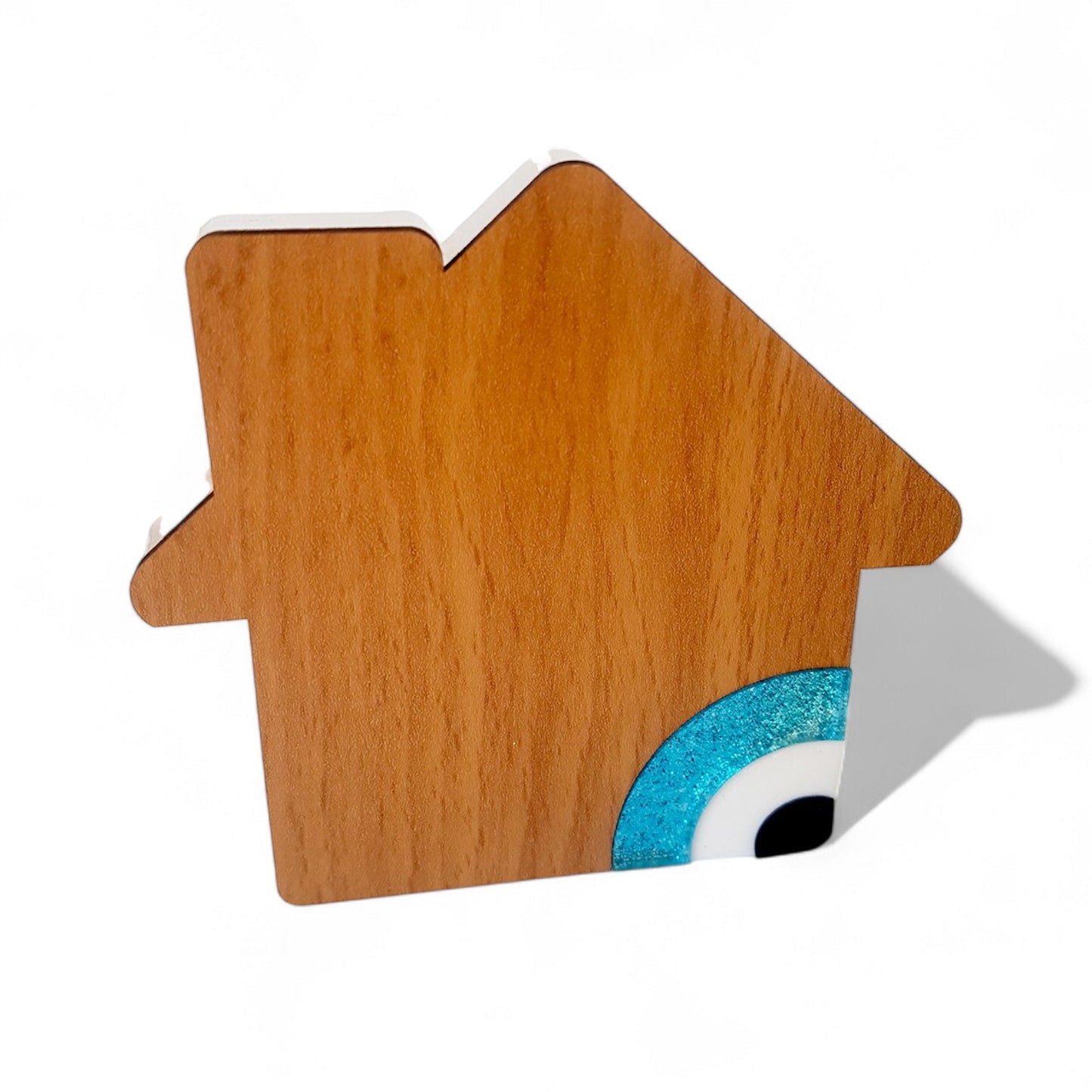 Wooden house-shaped object with a blue and white eye design on a white background