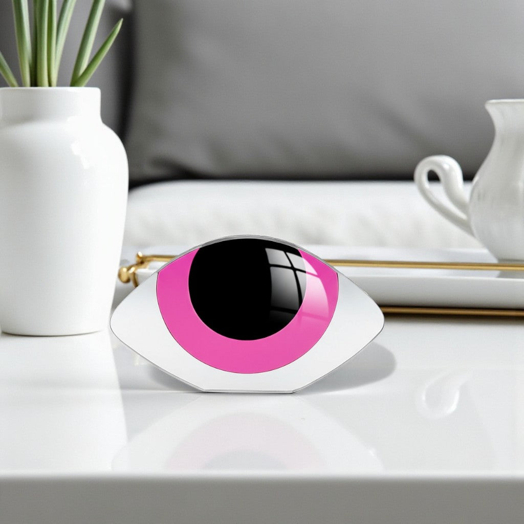 Decorative object shaped like a stylized eye with pink and black design on a surface.