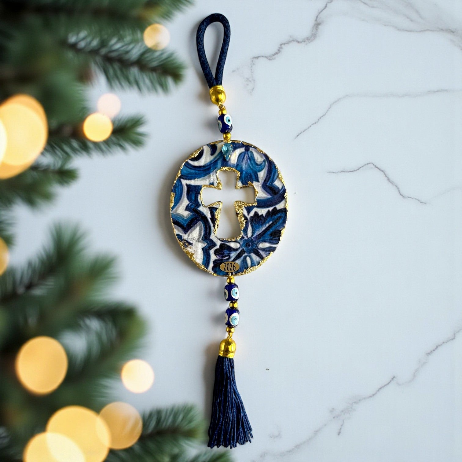 Γούρι 2026 οβάλ σταυρός με μάτια & φούντα – Greek Wishes Χονδρική So Cute by Dimi