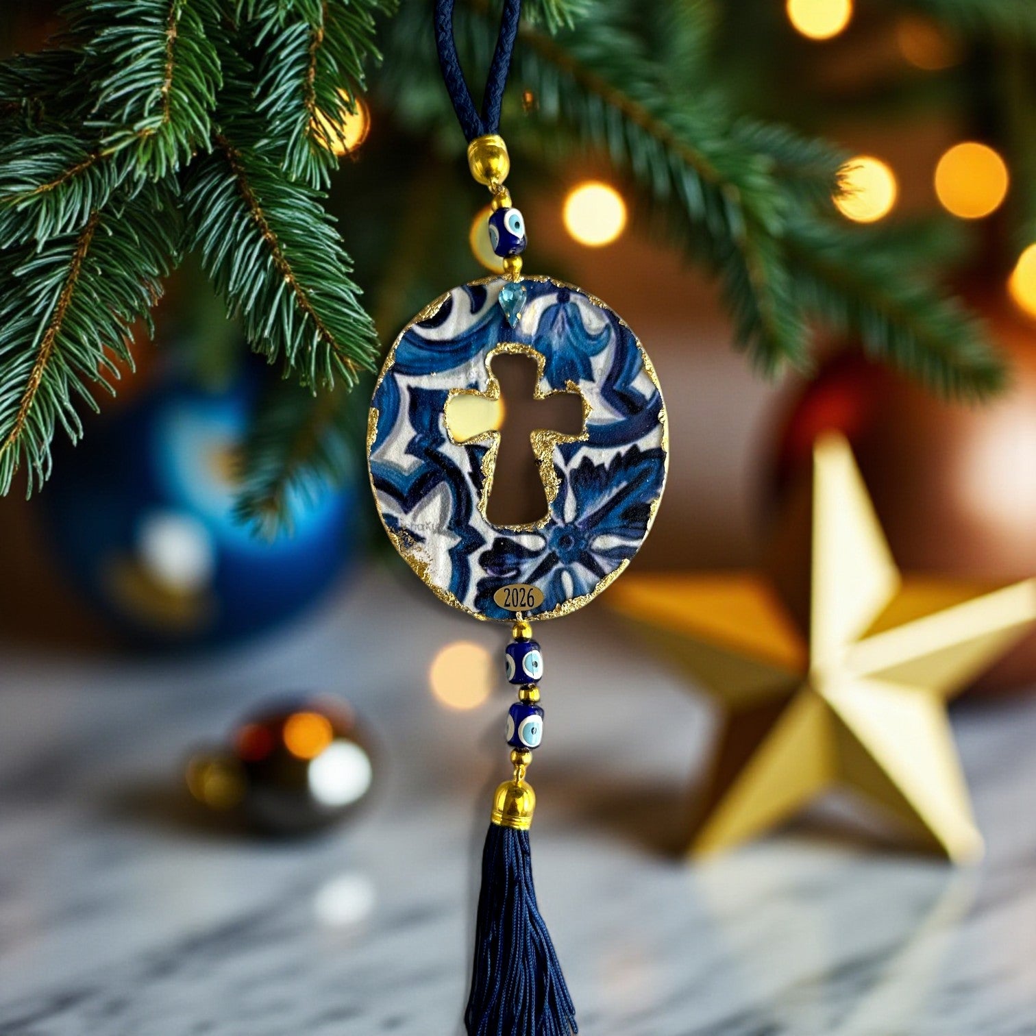 Γούρι 2026 οβάλ σταυρός με μάτια & φούντα – Greek Wishes Χονδρική So Cute by Dimi