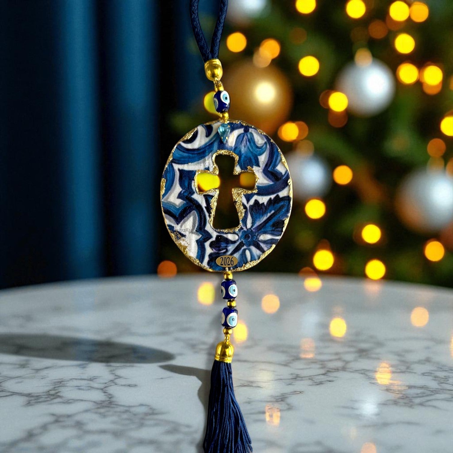 Γούρι 2026 οβάλ σταυρός με μάτια & φούντα – Greek Wishes Χονδρική So Cute by Dimi