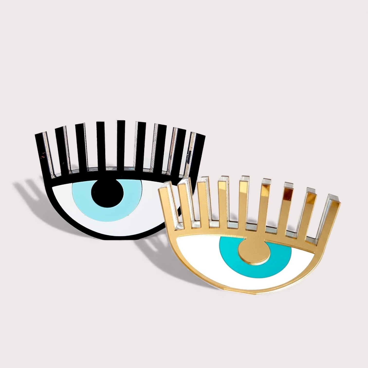 BStudio photo of two plexiglass evil eye table charms (black and gold) on soft neutral background – So Cute by Dimi.