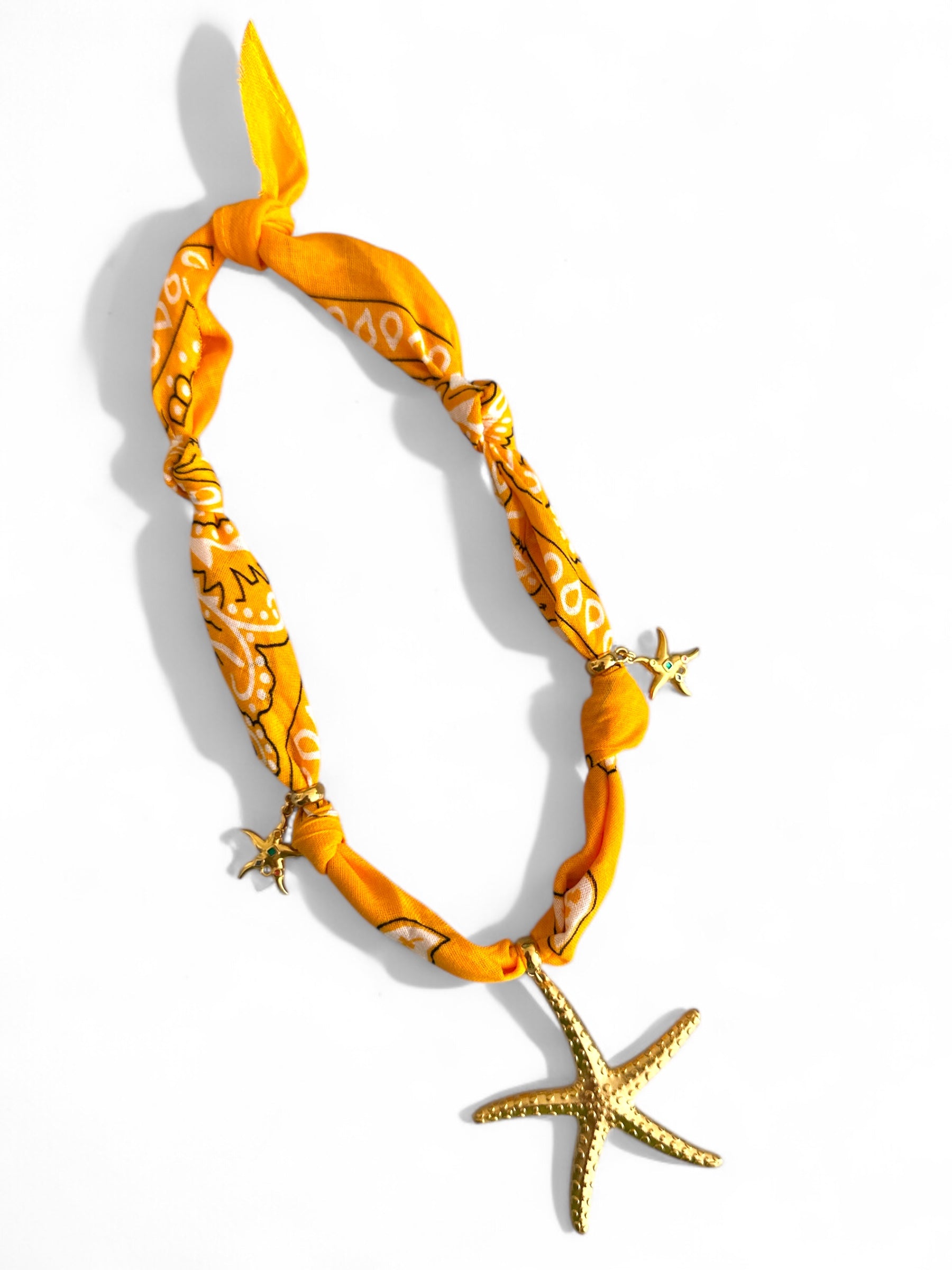 Yellow patterned bandana necklace with starfish decorations on a white background
