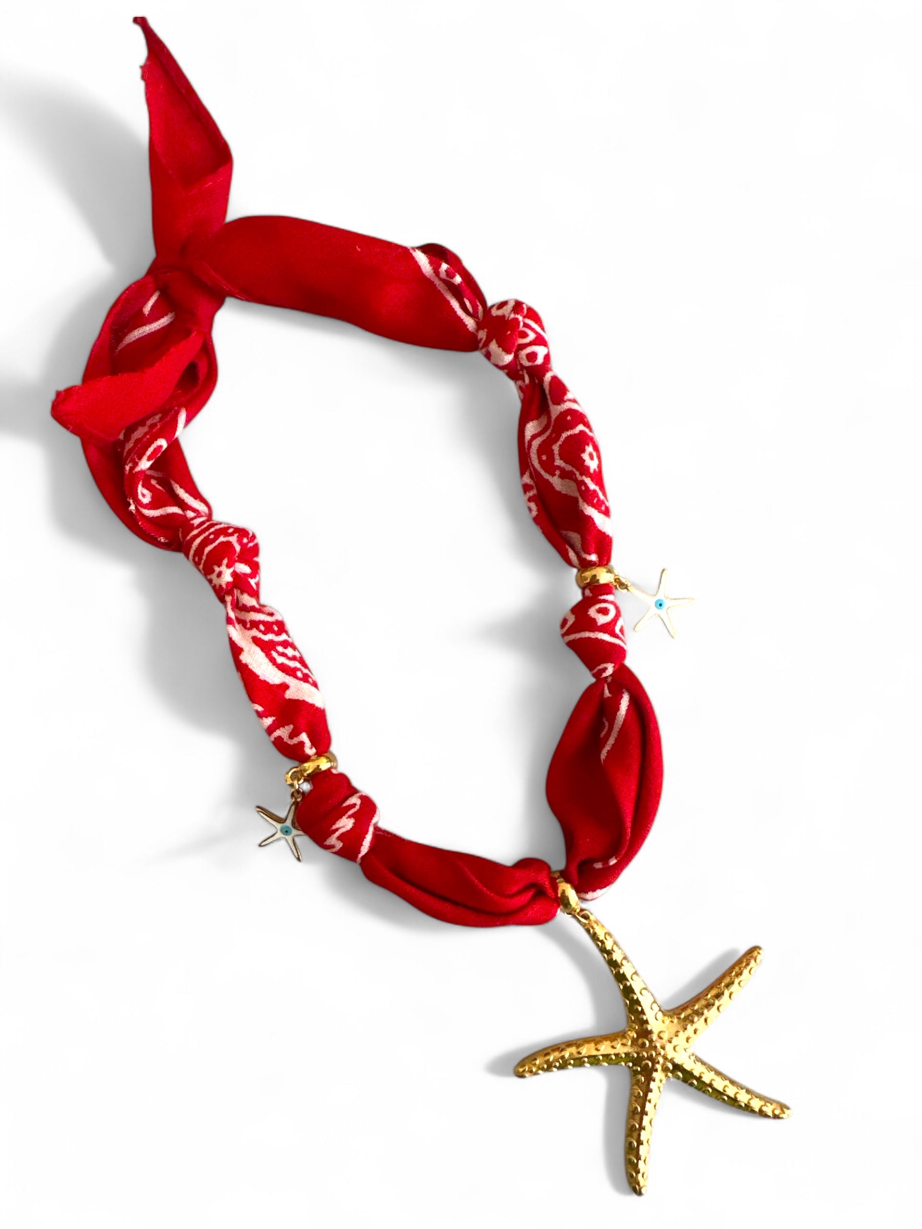 Red bandana necklace with a gold starfish pendant on a white background