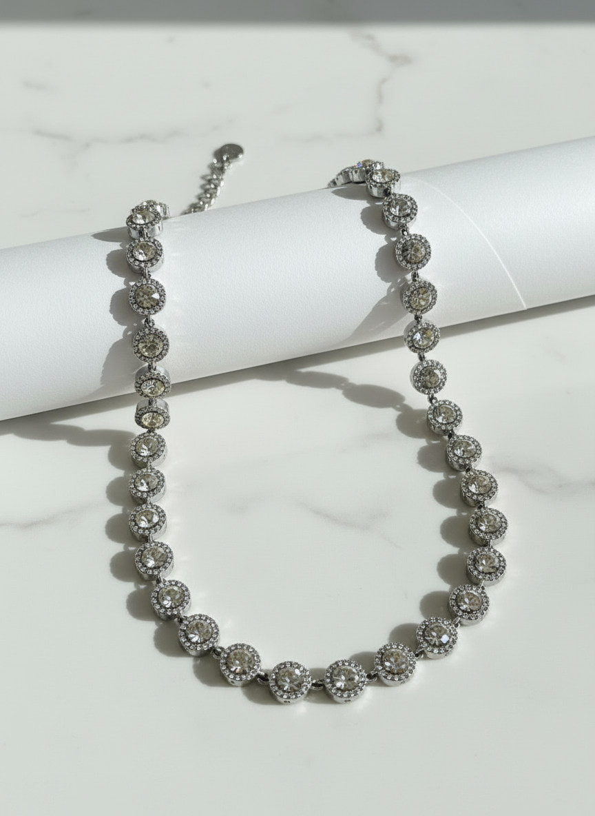 Silver steel necklce with clear zircon stones and rhinestones on a white marble surface