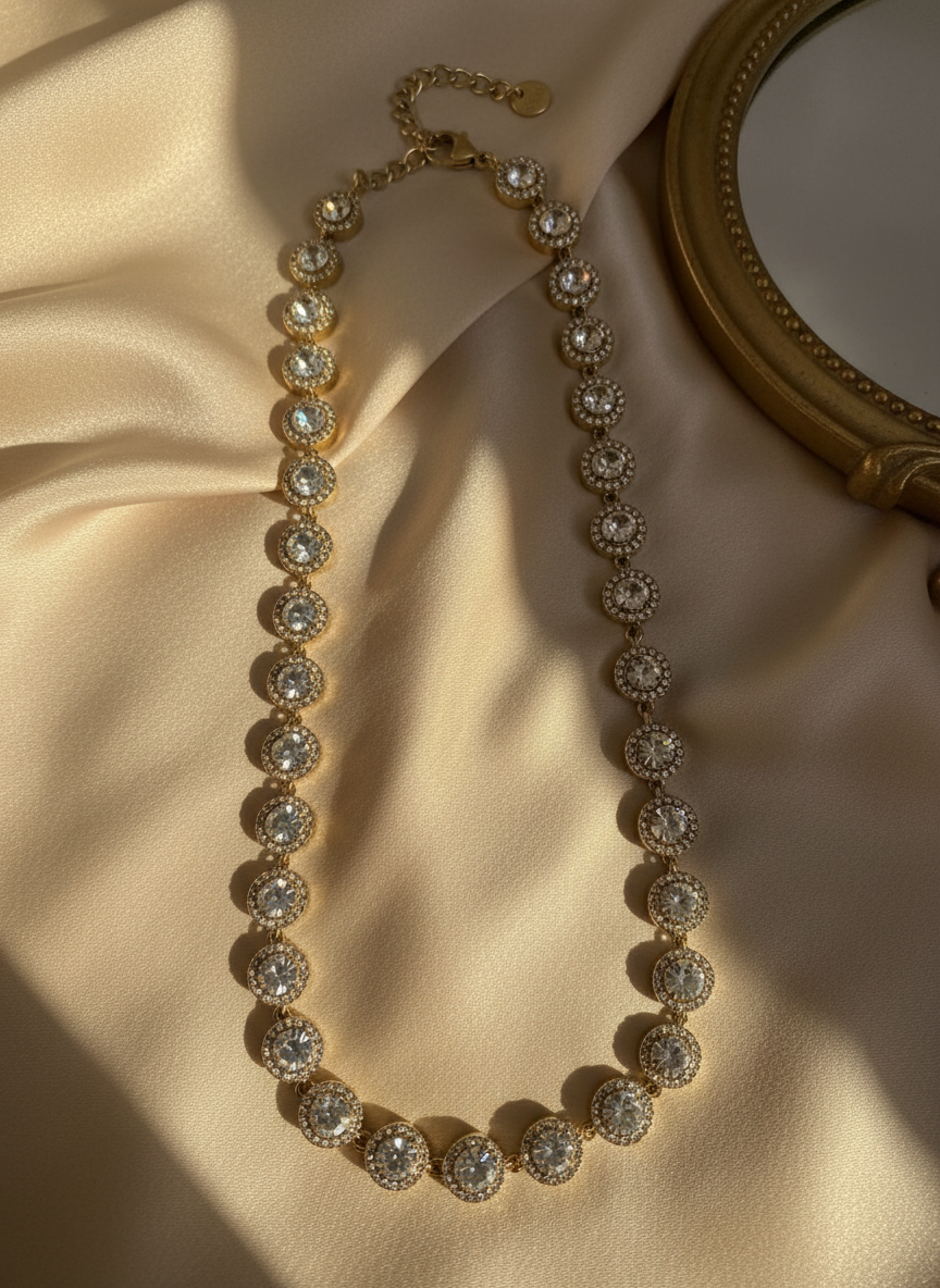 Gold steel necklace with clear zircon stones and rhinestones on a beige fabric background