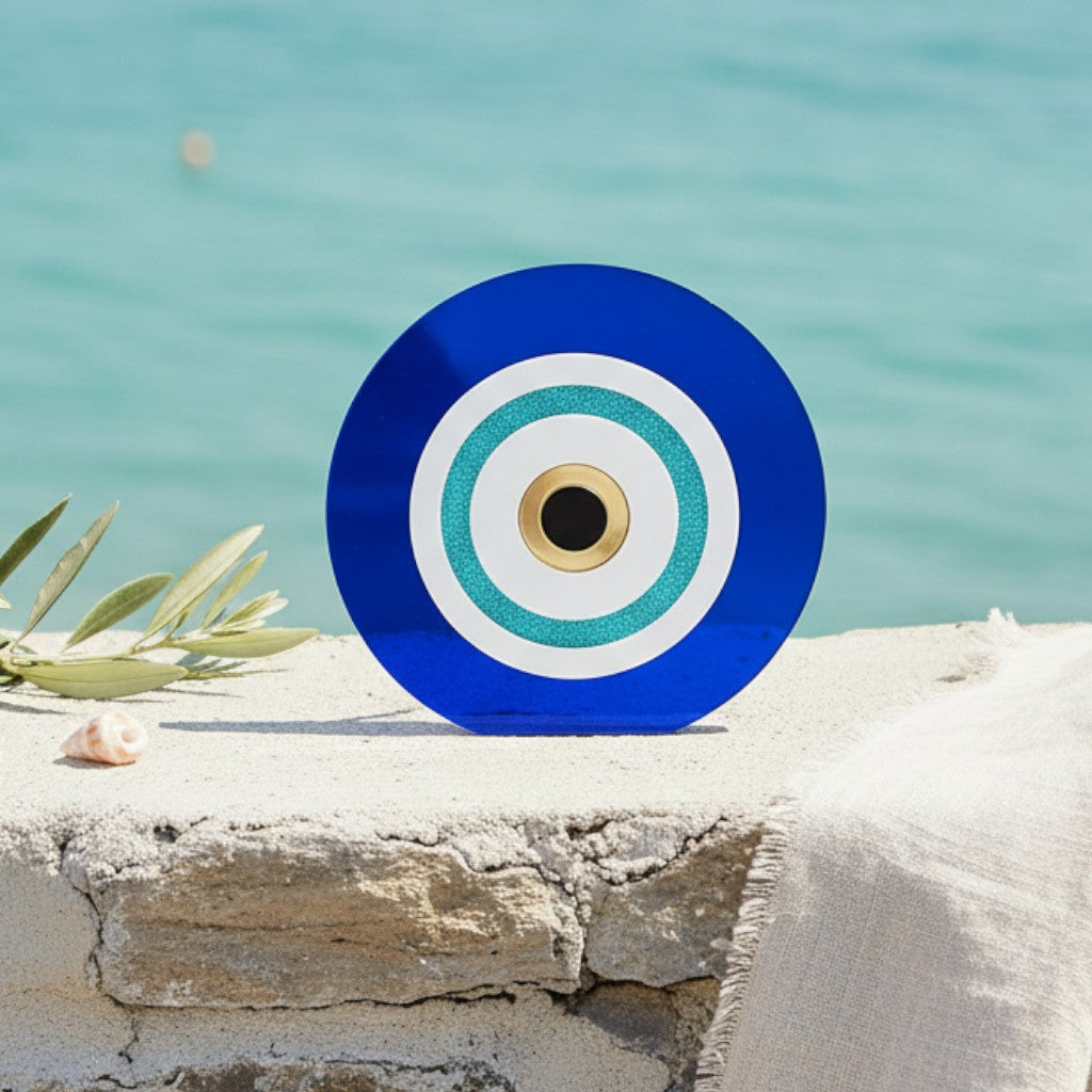 Αυτοστηριζόμενο μπλε ακρυλικό γούρι μάτι με τιρκουάζ λεπτομέρειες σε πέτρινη επιφάνεια δίπλα στη θάλασσα