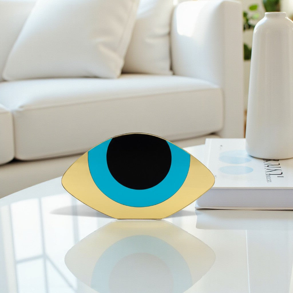 Decorative eye-shaped object on a coffee table with a white couch and vase in the background